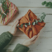 Furoshiki tissue wrapping of presents. Female hand holding a gift in eco friendly reusable fabric package. Small business, ethical shopping idea. Presents packed in plastic free. Zero waste lifestyle